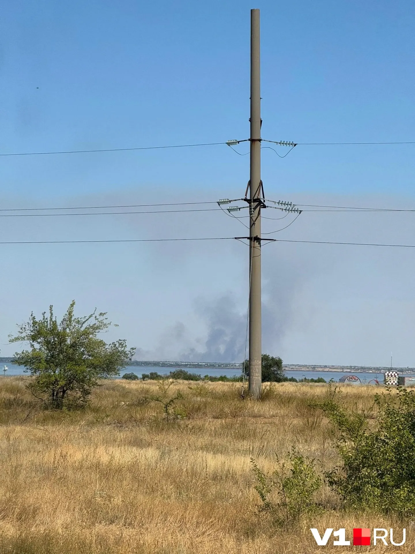 Возгорание сухой травы тушат пожарные; дым виден в окрестностях района.